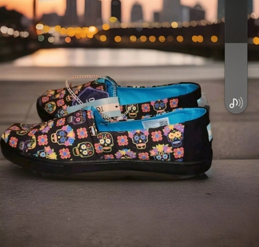 TOMS Dia De Los Muertos shoes featuring colorful sugar skull designs on a dark background