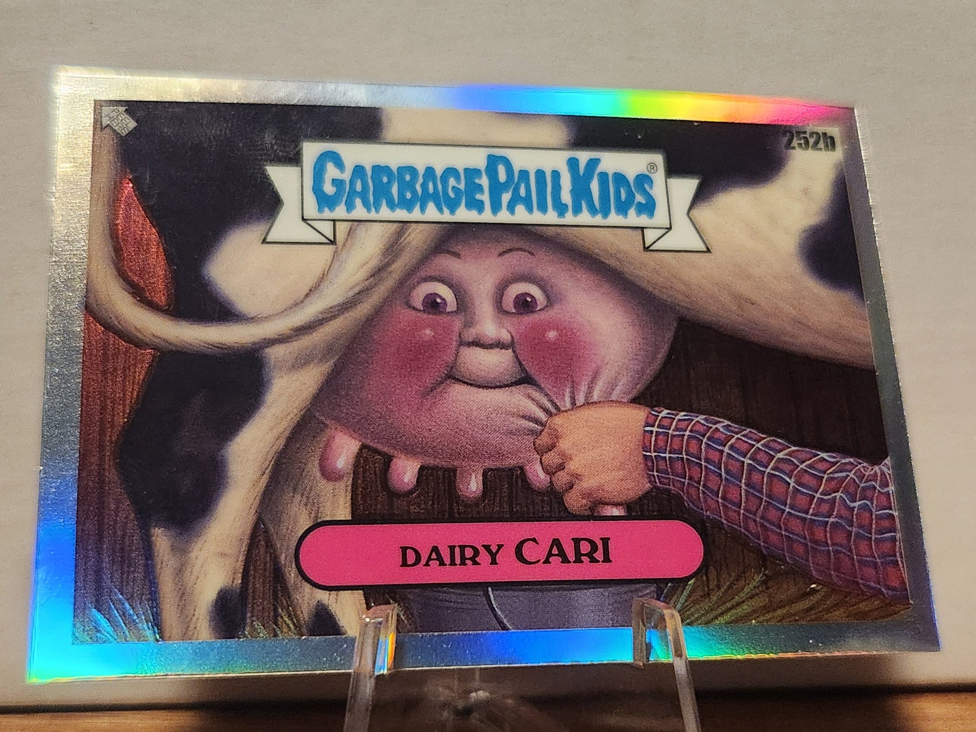 252B DAIRY CARI- GARBAGE PAIL KIDS-REFRACTOR card featuring a whimsical character with a cow background